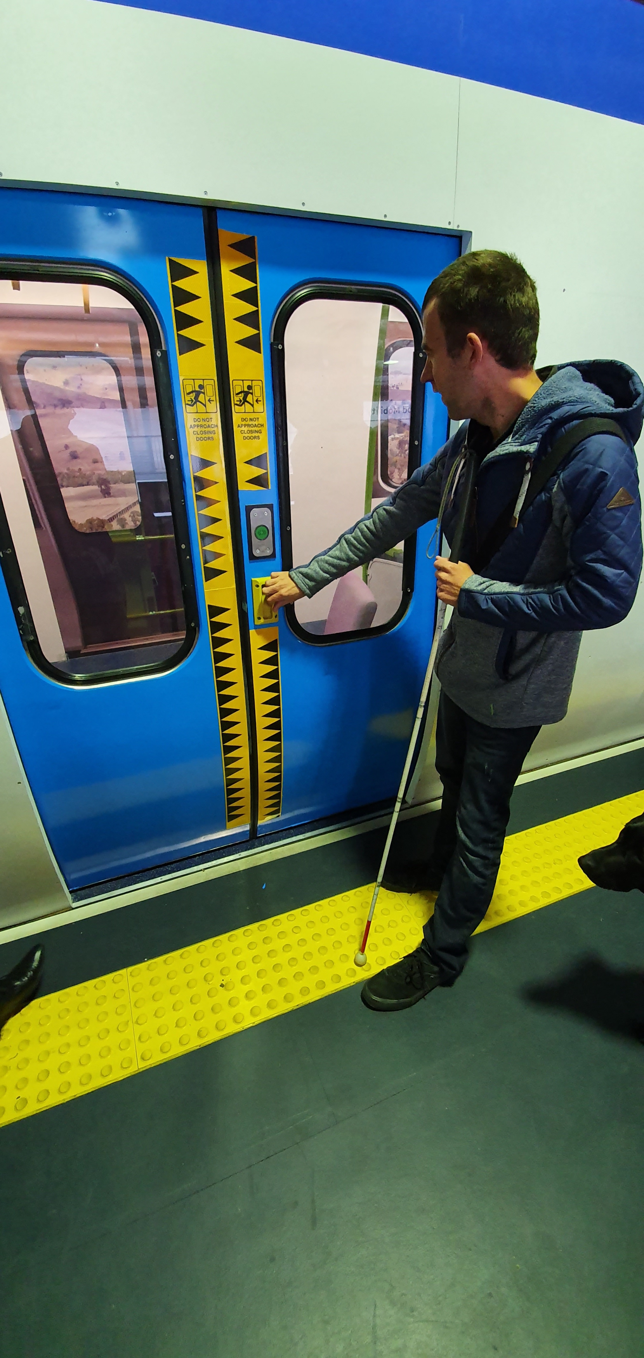 Shane, a client with Vision Australia, feels around a train door for the new button