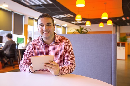 Image shows Vision Australia client Jack sitting at a desk using a tablet device. 
