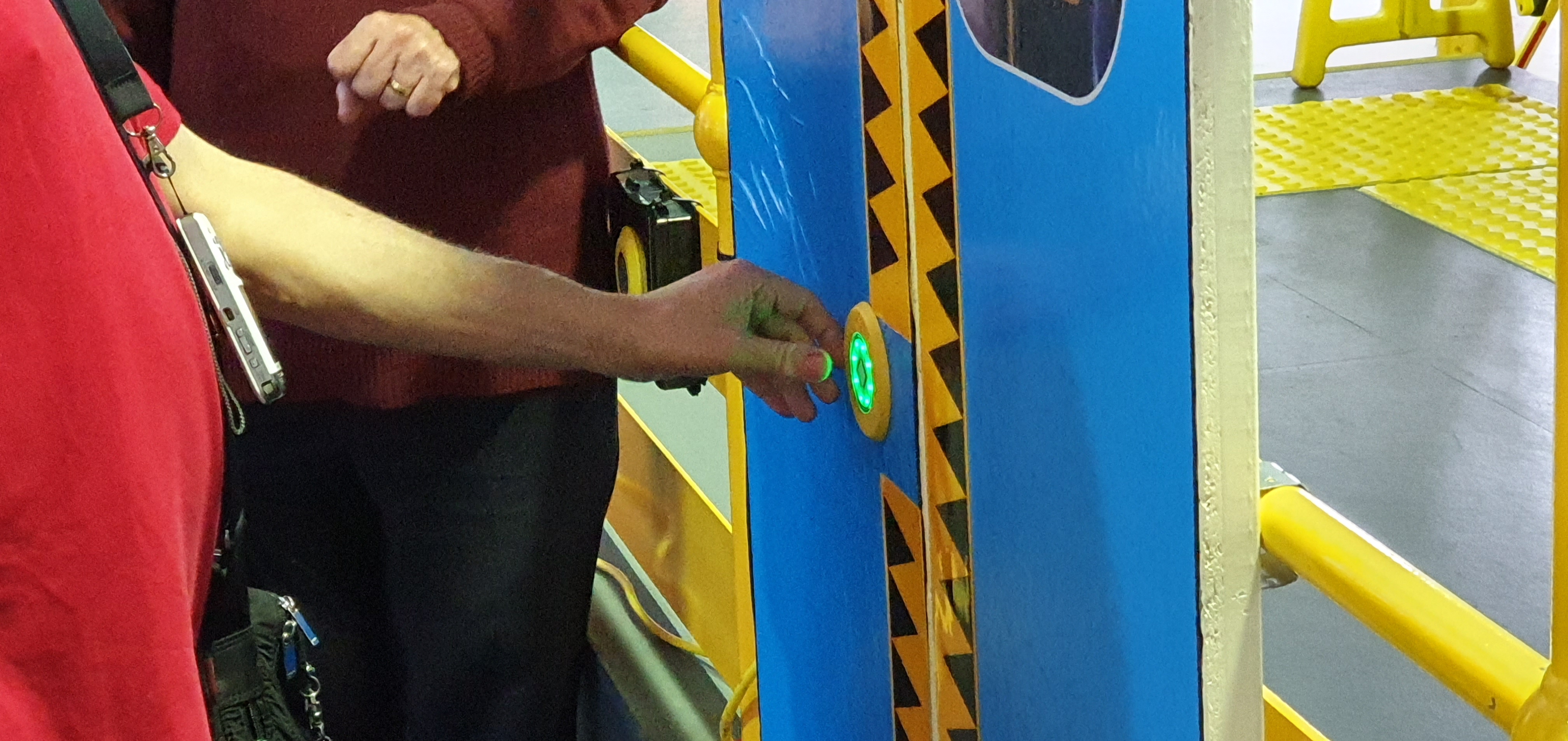 "A close-up of a hand pressing the open button on a train door."