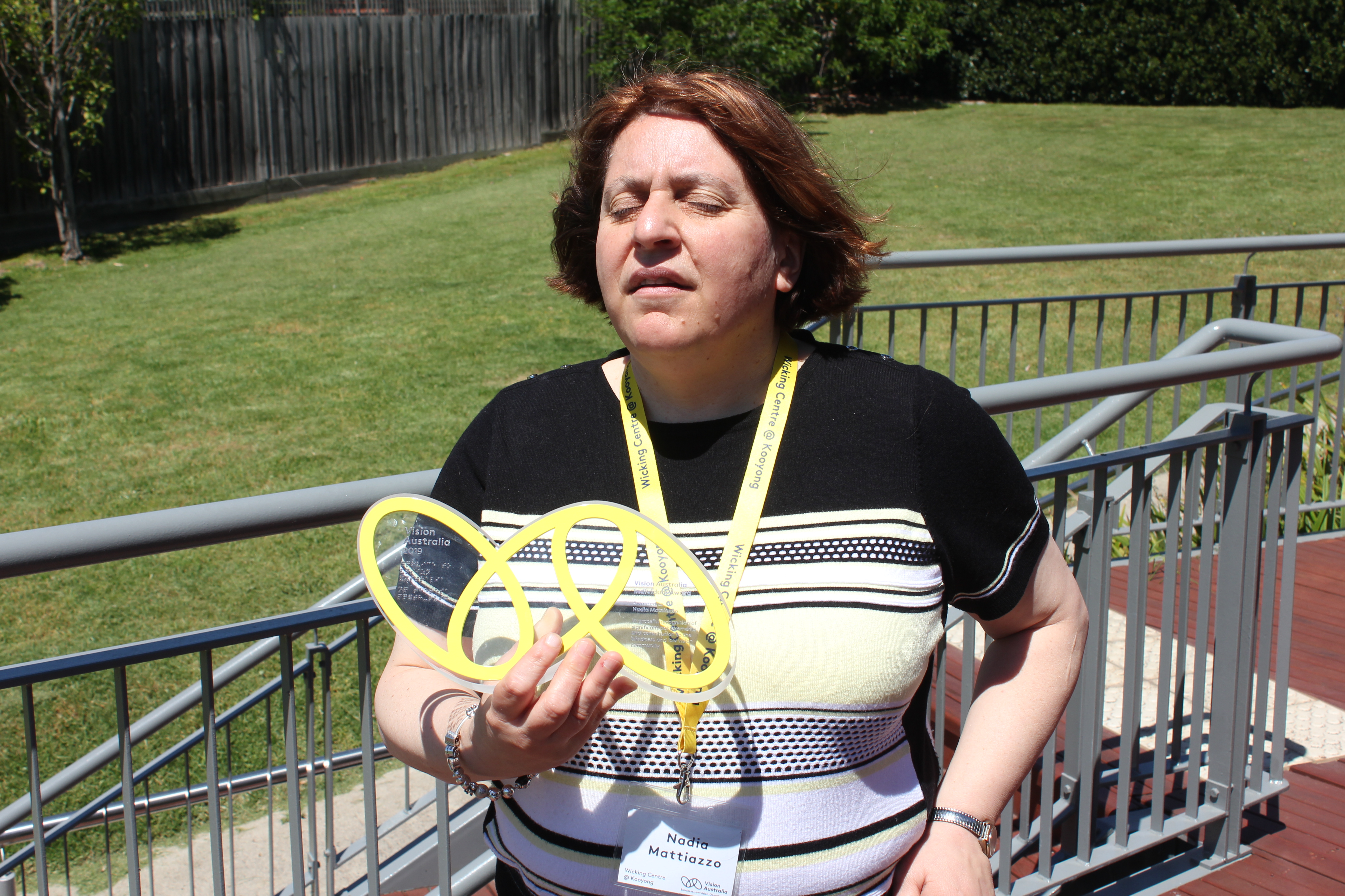 "VA Award winner Nadia, holding her award which takes the shape of the VA logo of 3 yellow ovals linked together"