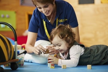 A young VA client plays with wooden blocks along with a VA client