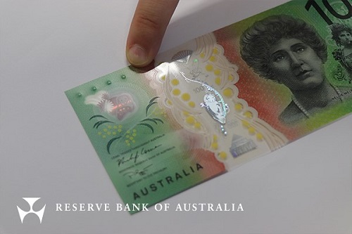 A finger on the four dots of the tactile feature of the new $100 bill