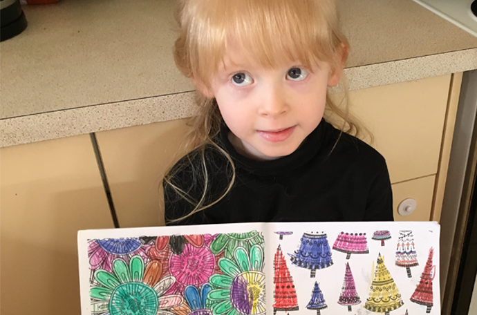 Amelia holding her colourful artwork