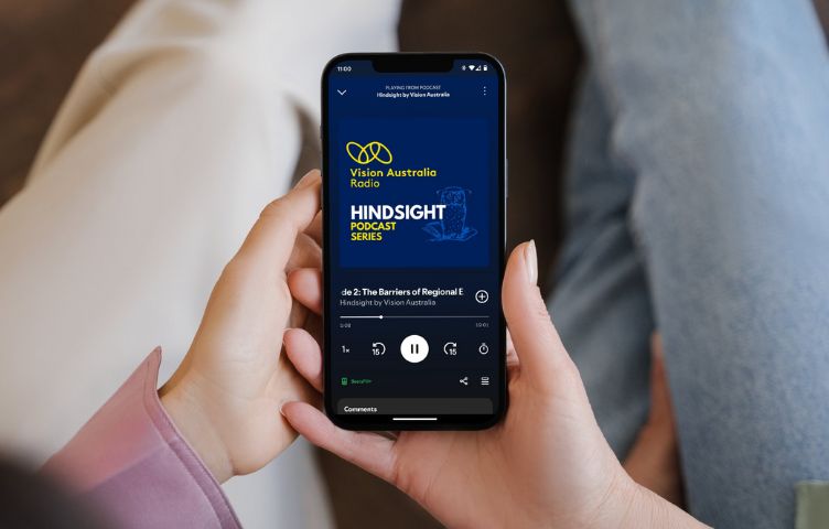 Two people sit on a couch both holding a phone together, listening to Vision Australia’s Hindsight podcast on Spotify. 