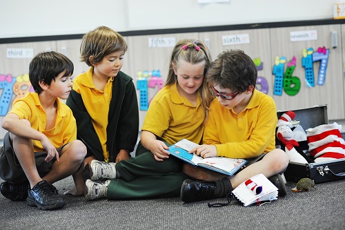 Four primary school students sit together reading a Feelix library book