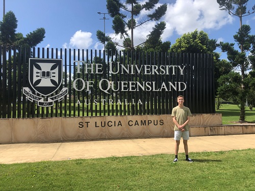 Levi standing in front of a large University of Queensland sign