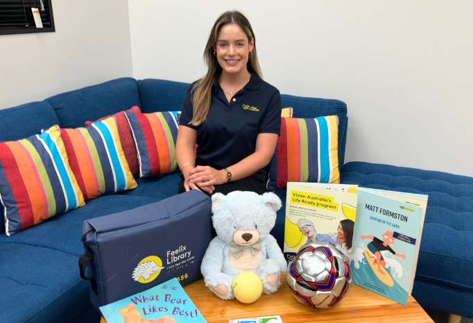 Kaylie is sitting on a blue couch, surrounded by toys and games she uses in her practice