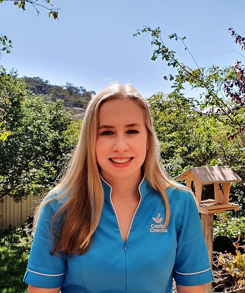 Caitlin in her blue pharmacy uniform facing the camera