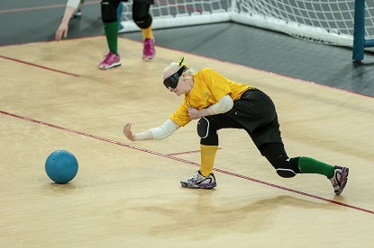 An Australian female goalball player rolls the ball towards her opponents