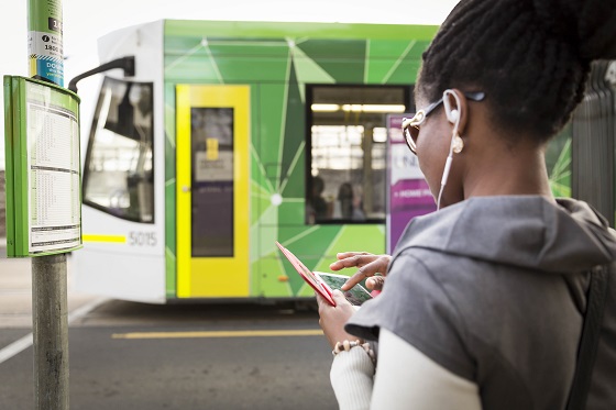 Woman uses a smart phone as she waits for a tram