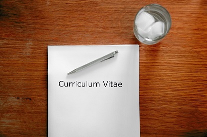 Image shows a CV on a table next to a glass of water. 