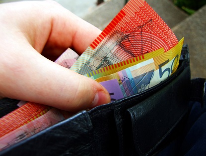 A hand removes Australian banknotes from a wallet