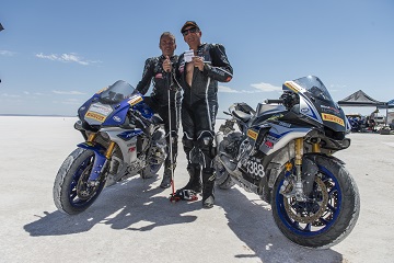Kevin Magee and Ben Felten in motorcycle leathers stand between their motorbikes at Lake Gardiner