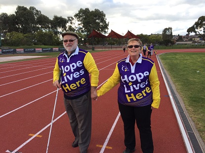 Martin, with his white cane, and Pat standing on a running track