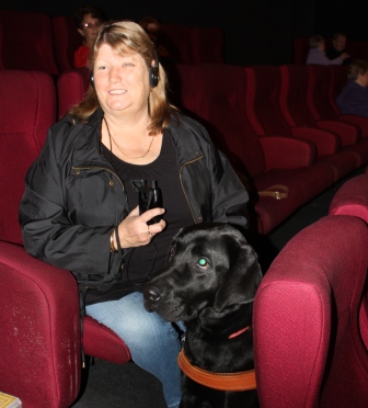 Photo of Rhonda and dog guide Cameron sitting inside the cinema