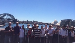 Group of people standing in front of a view of the Sydney Harbour as part of their day out for White Cane Day