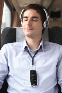 man on train with headphones on listening to audio books from his BookSense DAISY player that is hanging from his neck