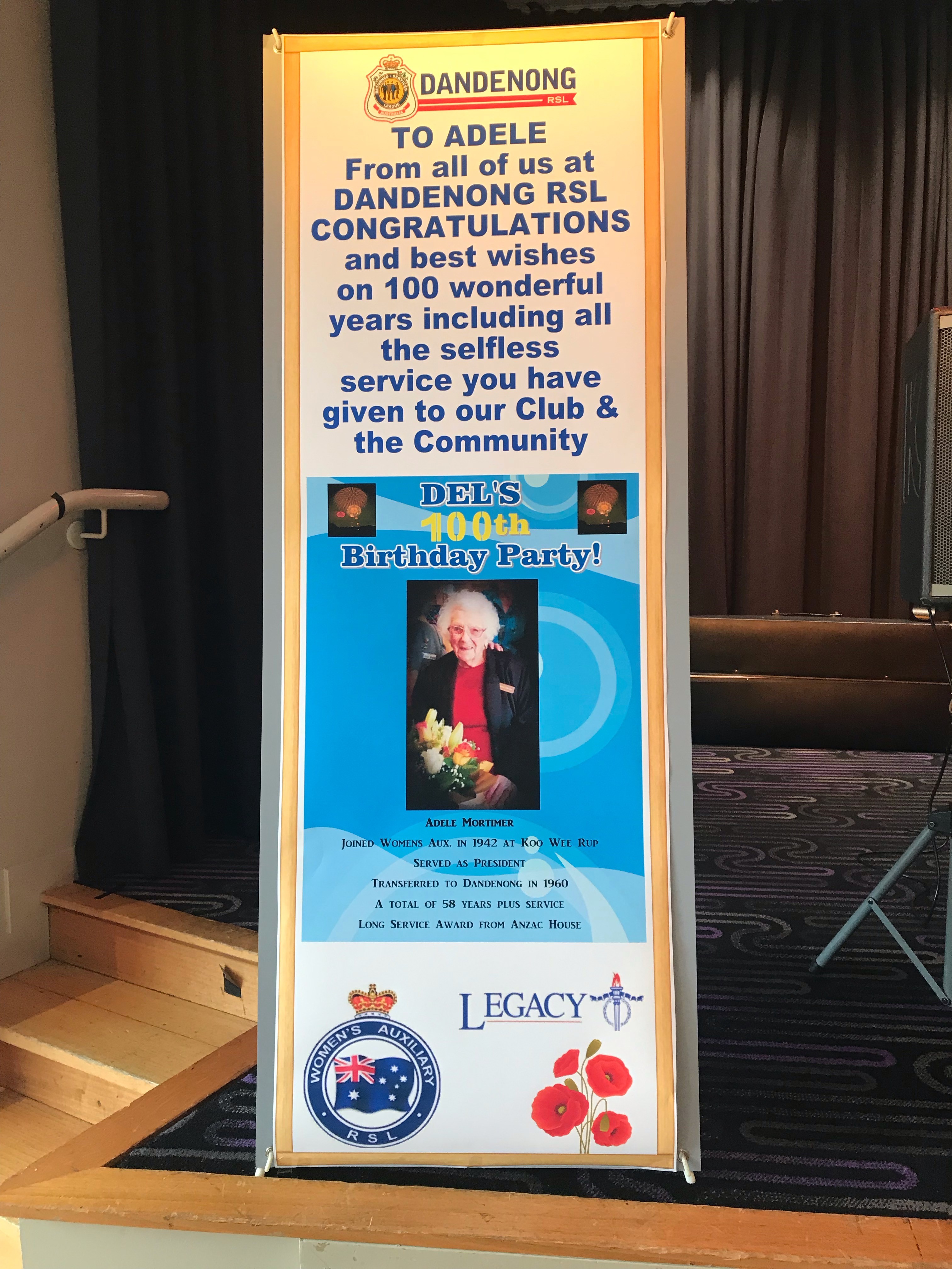 "A sign celebrating Adele that reads: "TO ADELE, From all of us at Dandenong RSL , CONGRATULATIONS, and best wishes on 100 wonderful years including all the selfless service you have given to our club and the community"
