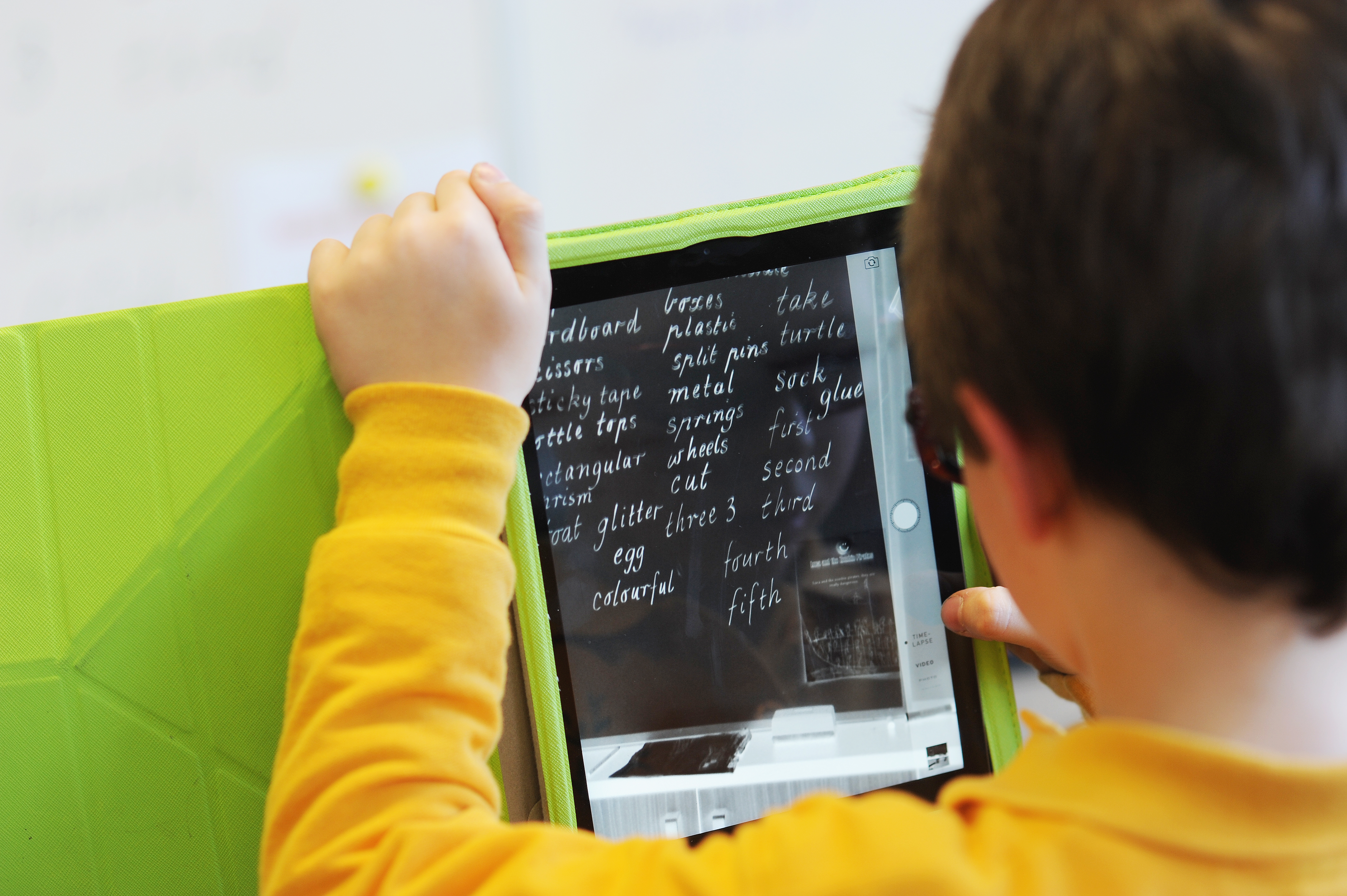 Boy using a tablet with magnification, he is looking at his weekly spelling words