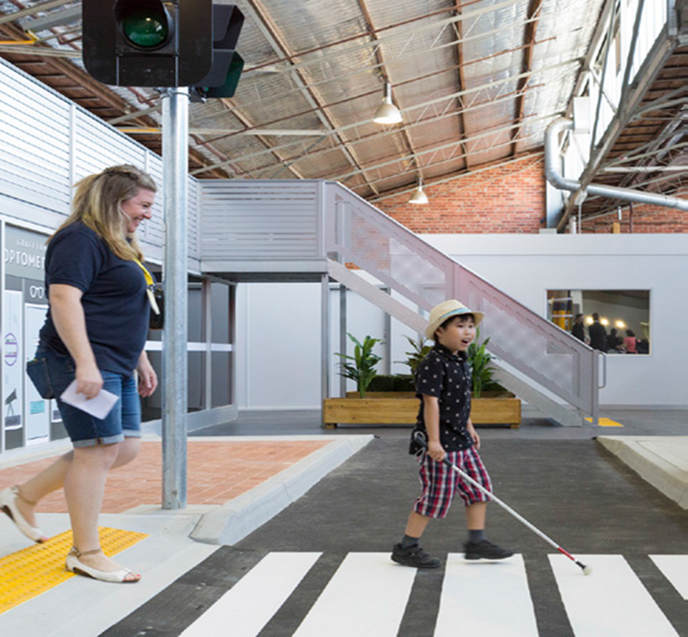 Child walking with cane at the Leigh Garwood Centre supervised by a Vision Australia professional