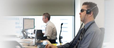 A blind man working in an office with another staff member in the background