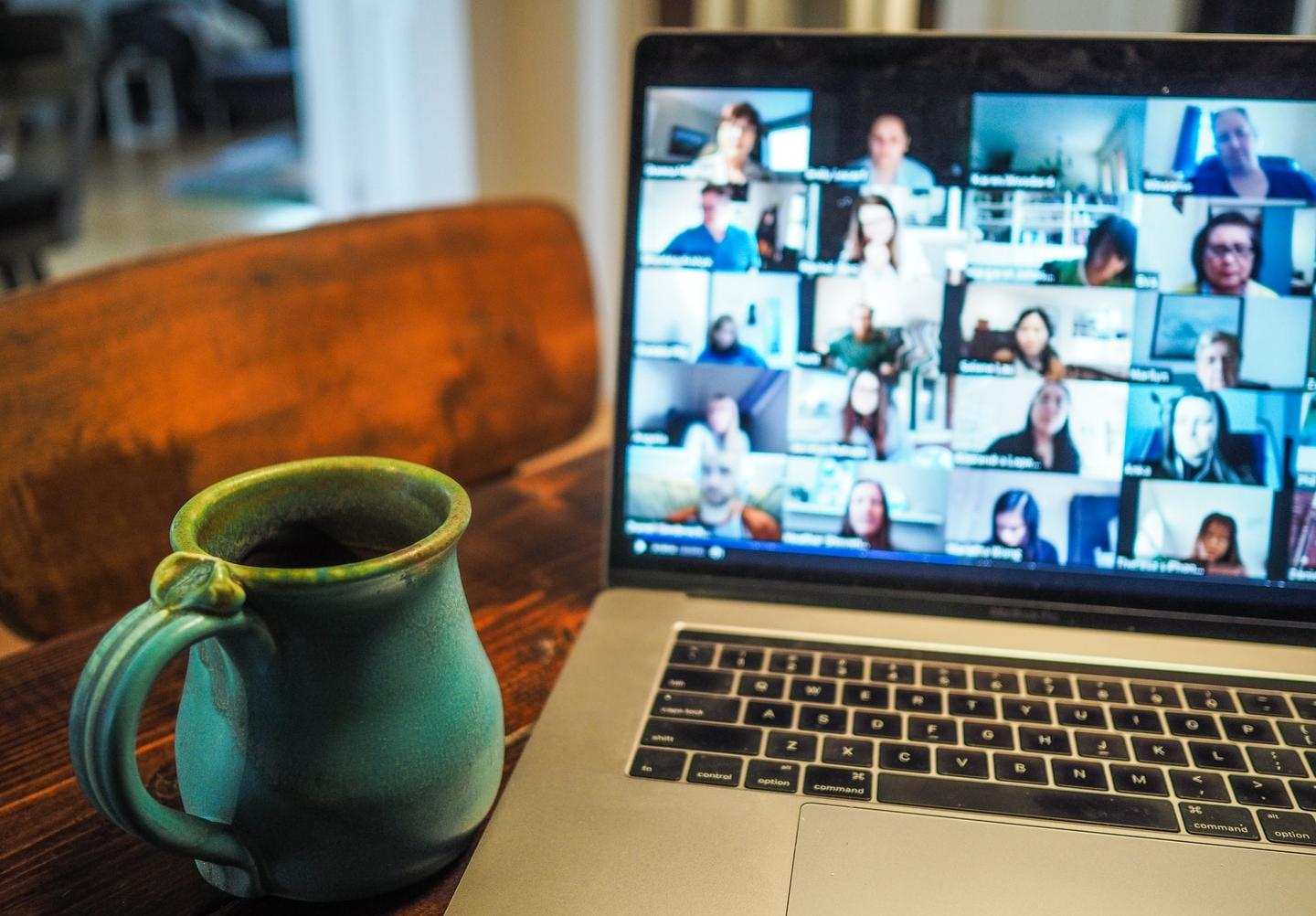 Cup of tea next to an open laptop where screen is full of video conferencing participants faces