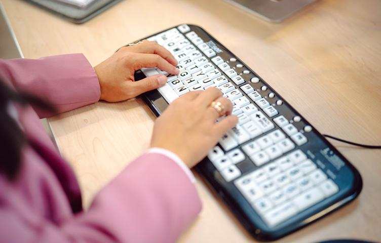 Hands typing on a large font keyboard