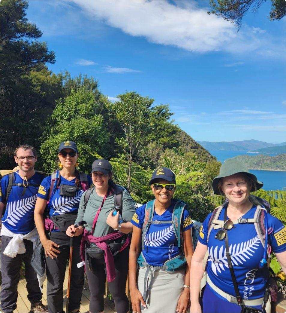 5 Trek for Vision participants standing in front of a bright blue bay