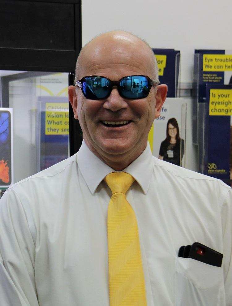 Rolf Geerling smiles wearing sunglasses and a yellow tie.