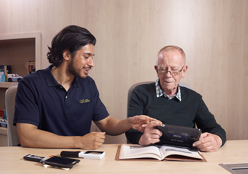 A Vision Australia expert demonstrating different magnifiers to an older male client